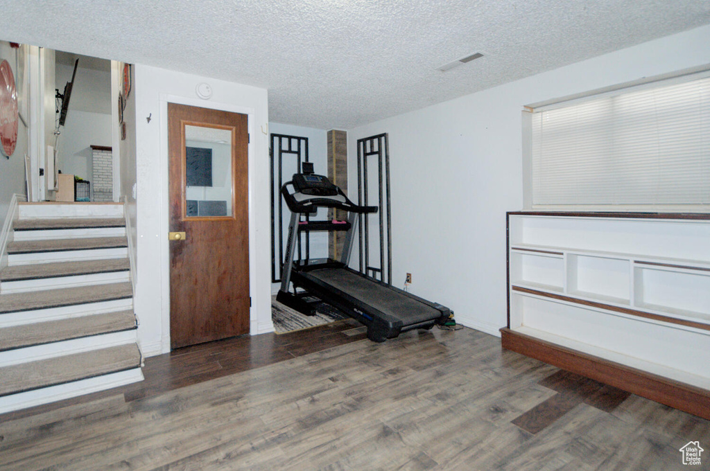 Workout room with dark hardwood / wood-style floors and a textured ceiling
