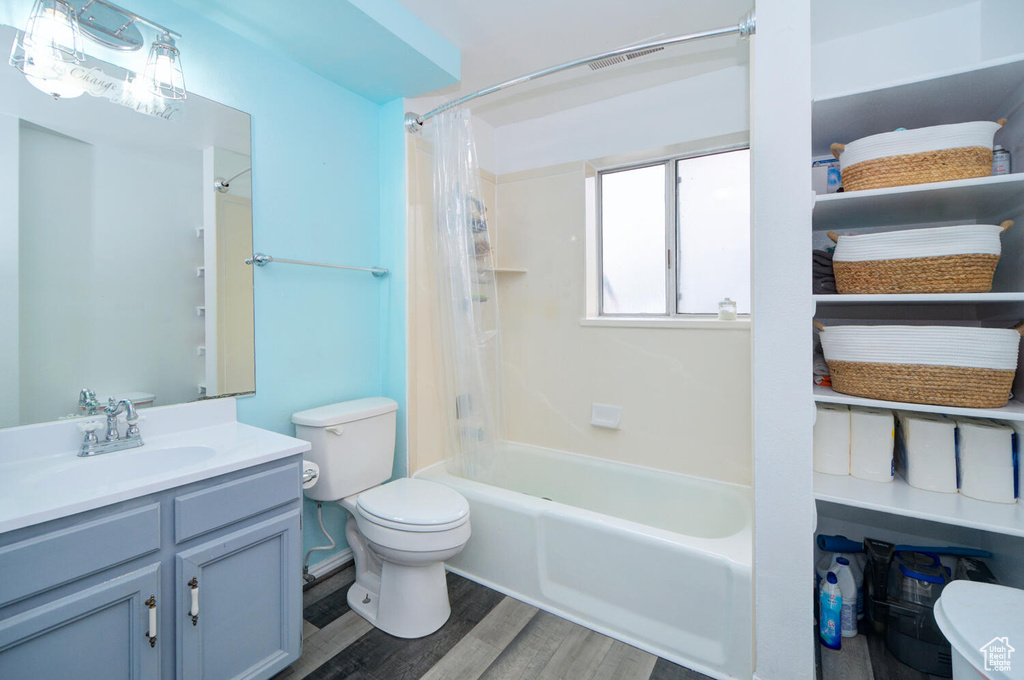 Full bathroom with shower / bath combo, wood-type flooring, toilet, and vanity