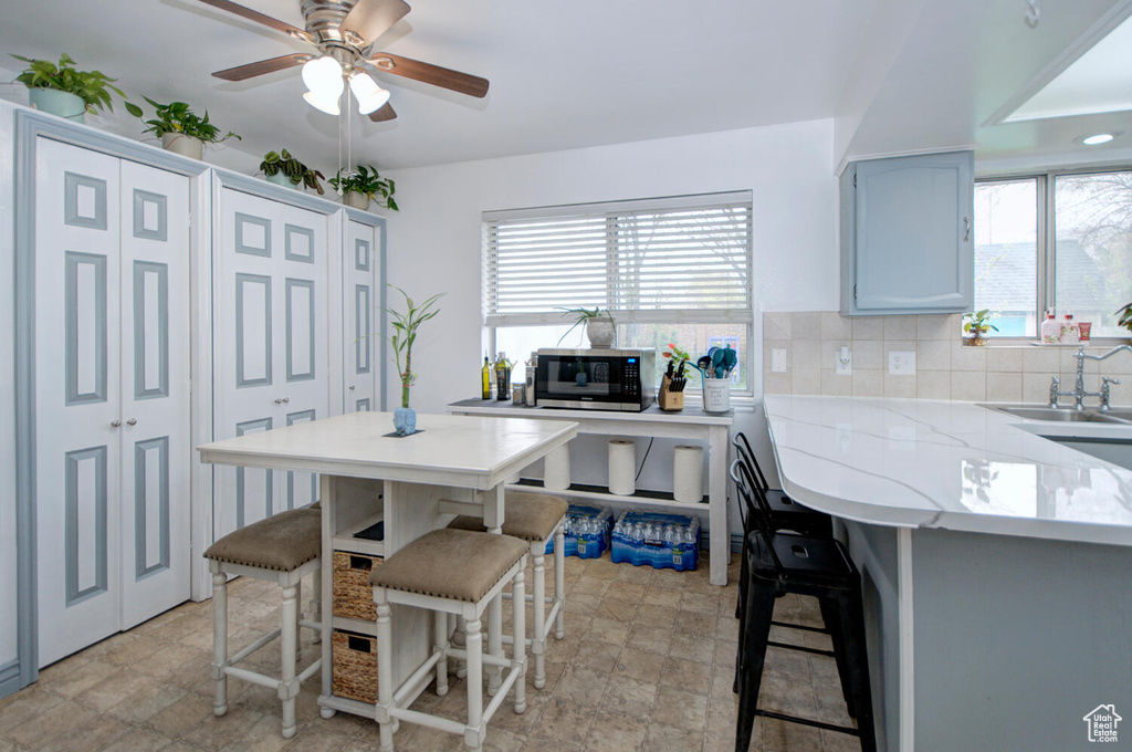 Kitchen featuring tasteful backsplash, ceiling fan, a breakfast bar area, and light tile flooring
