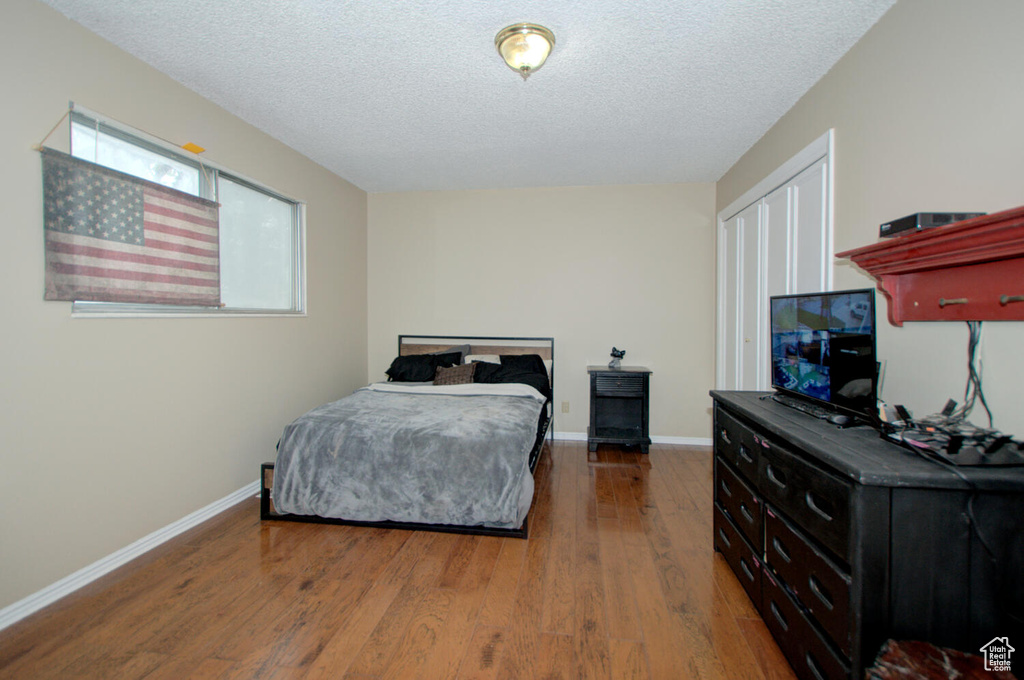 Bedroom with dark hardwood / wood-style floors and a textured ceiling