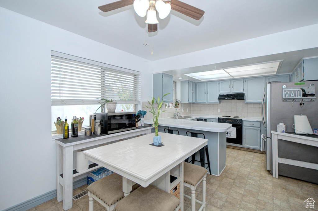 Kitchen featuring backsplash, appliances with stainless steel finishes, light tile floors, sink, and ceiling fan