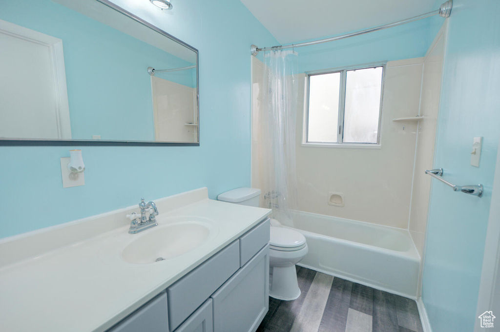 Full bathroom with hardwood / wood-style floors, toilet, large vanity, and shower / tub combo with curtain