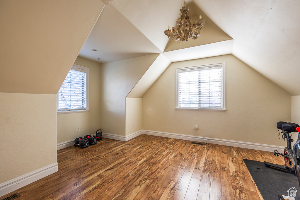 Bonus room with a notable chandelier, dark hardwood / wood-style floors, and plenty of natural light