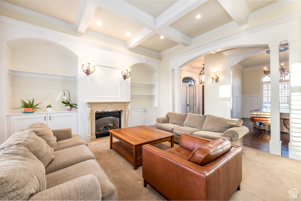 Carpeted living room featuring coffered ceiling, beamed ceiling, a premium fireplace, built in features, and ornamental molding