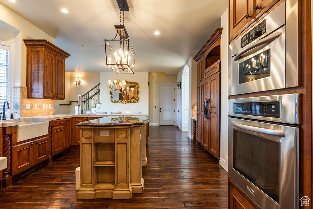 Kitchen featuring hanging light fixtures, a kitchen island, dark hardwood / wood-style floors, and a chandelier