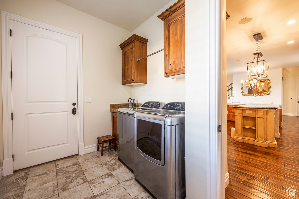 Laundry area featuring independent washer and dryer, an inviting chandelier, light tile flooring, and cabinets