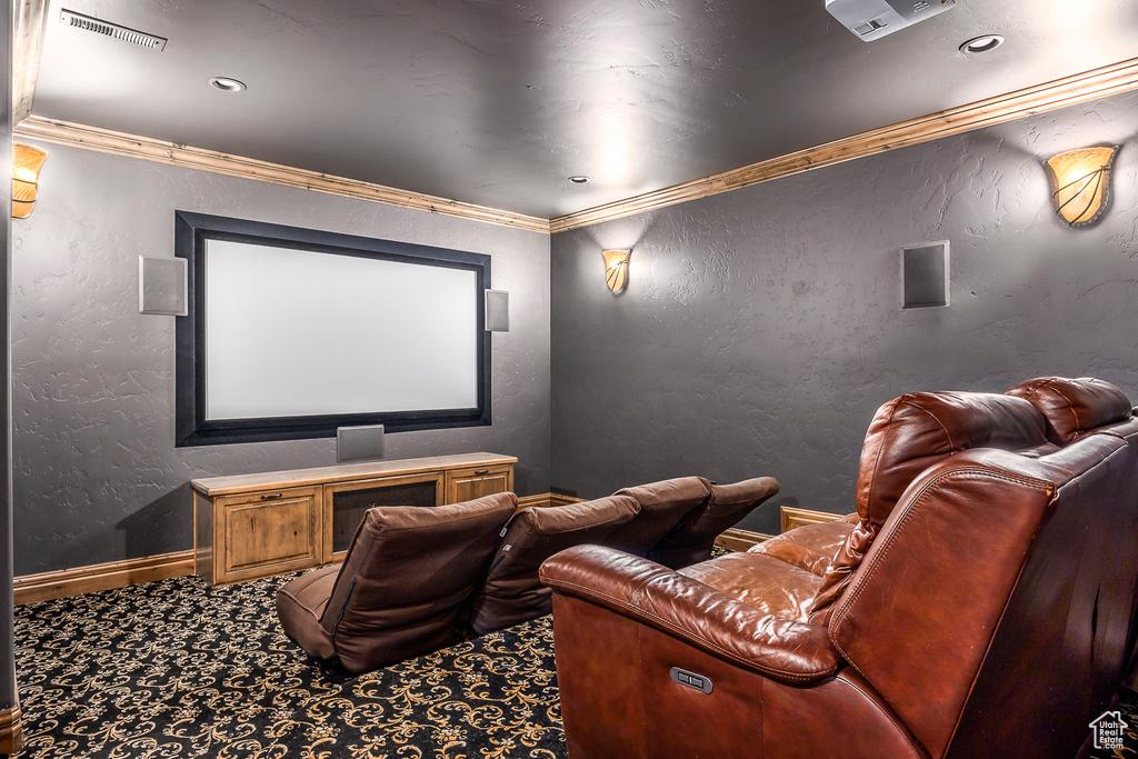 Home theater room with crown molding and carpet