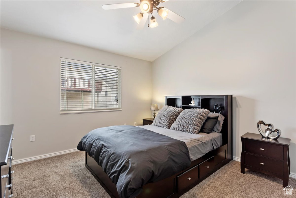 Bedroom featuring ceiling fan, light carpet, and vaulted ceiling
