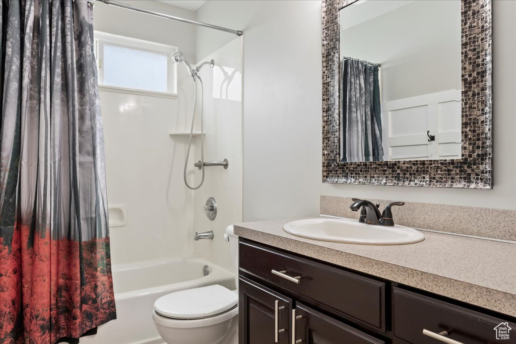 Full bathroom featuring shower / bathtub combination with curtain, oversized vanity, and toilet