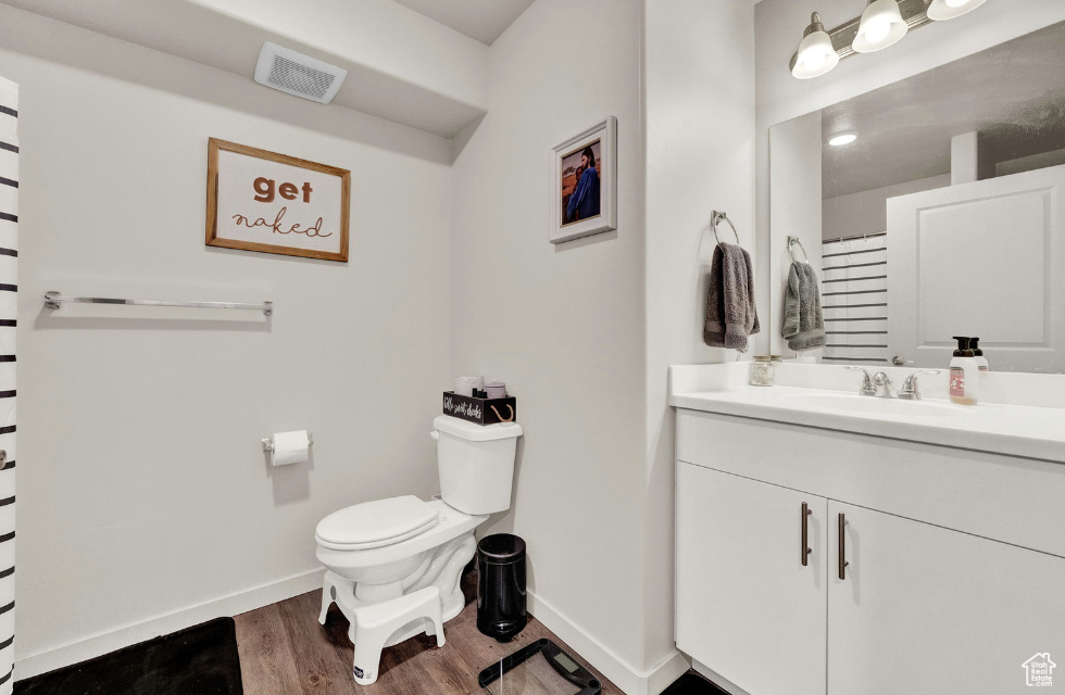 Bathroom with oversized vanity, toilet, and hardwood / wood-style flooring