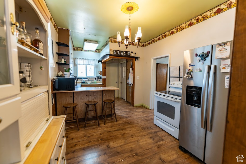 Kitchen featuring an inviting chandelier, dark wood-type flooring, electric stove, decorative light fixtures, and stainless steel fridge with ice dispenser