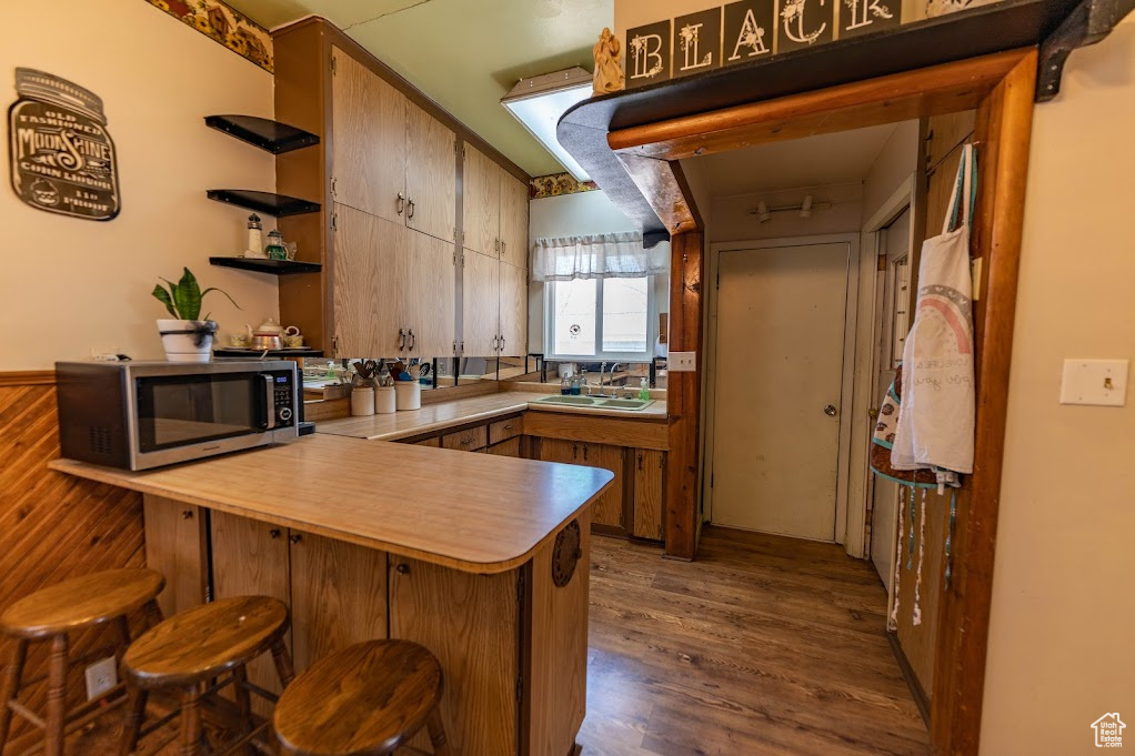 Kitchen with dark hardwood / wood-style flooring, sink, kitchen peninsula, and a kitchen breakfast bar