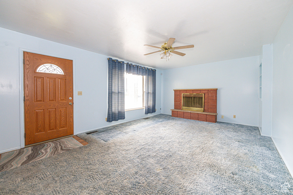 Carpeted entryway featuring ceiling fan and a fireplace