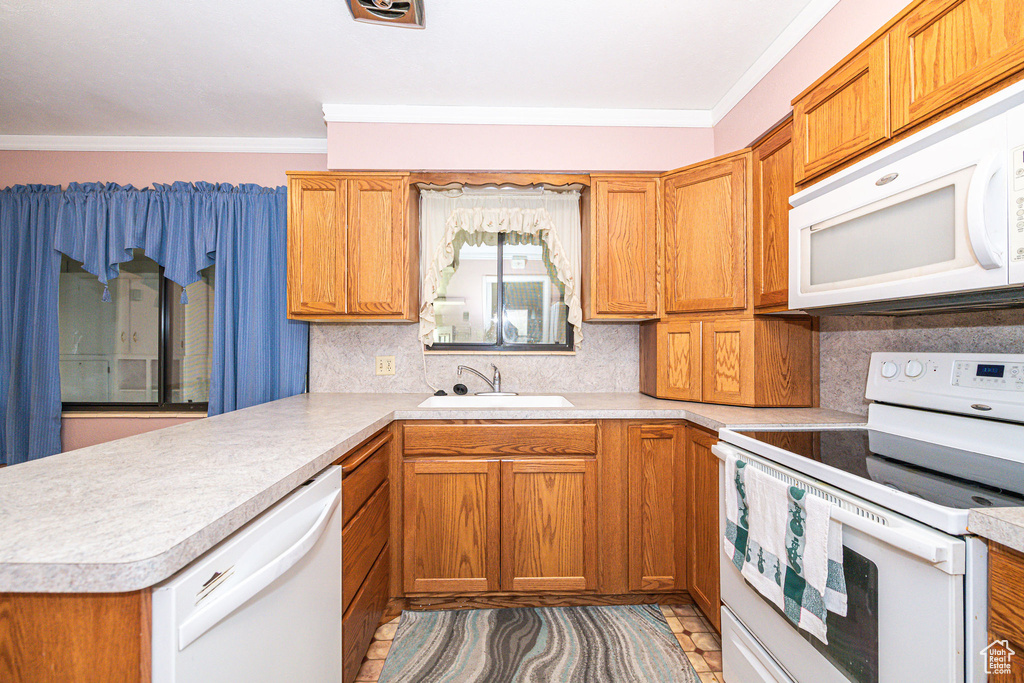 Kitchen with tasteful backsplash, sink, kitchen peninsula, white appliances, and ornamental molding