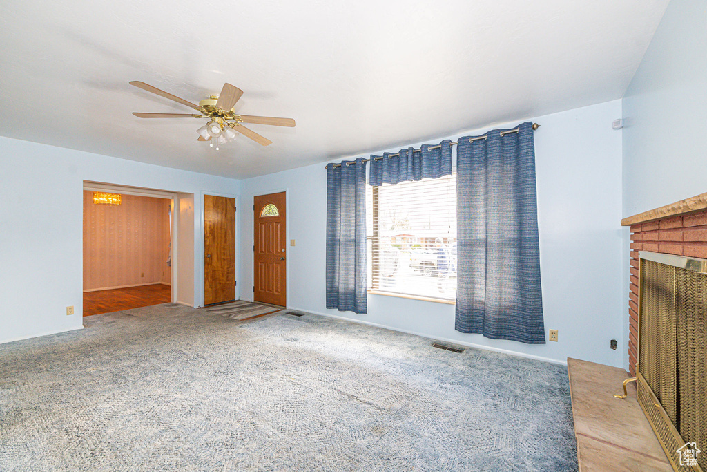 Unfurnished living room with ceiling fan, a fireplace, and light colored carpet