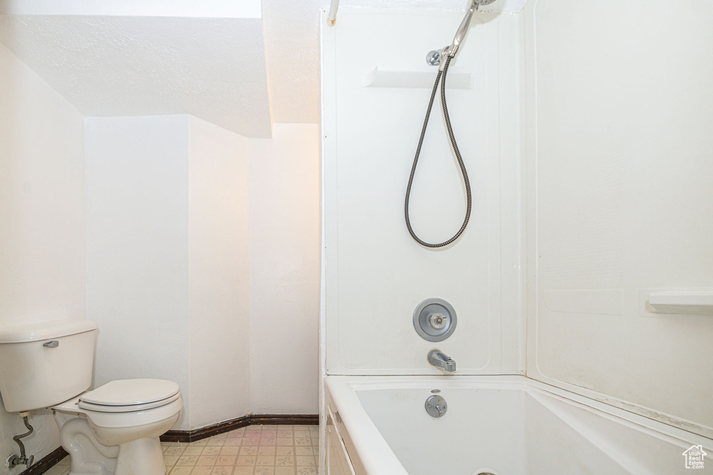 Bathroom featuring tile flooring, toilet, and washtub / shower combination