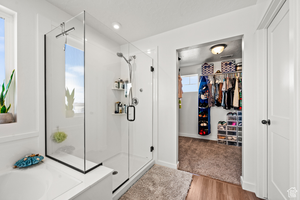 Bathroom featuring plus walk in shower, hardwood / wood-style flooring, and a wealth of natural light