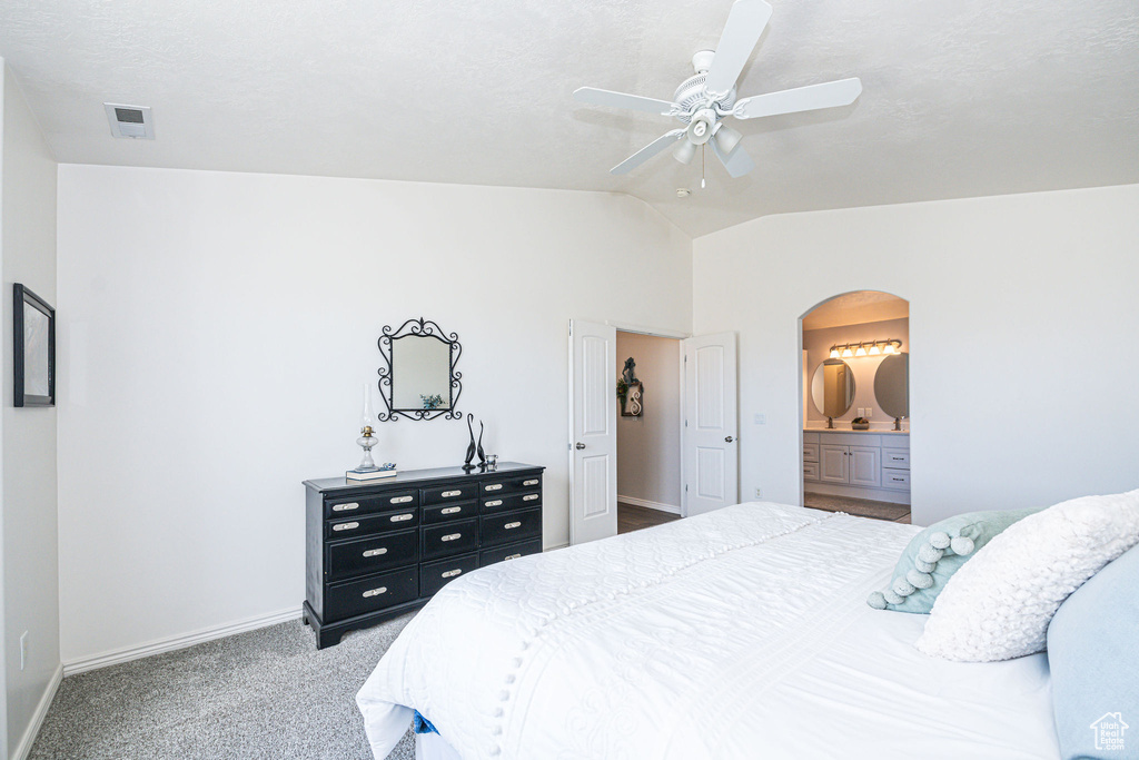 Bedroom featuring ceiling fan, lofted ceiling, light colored carpet, and ensuite bath