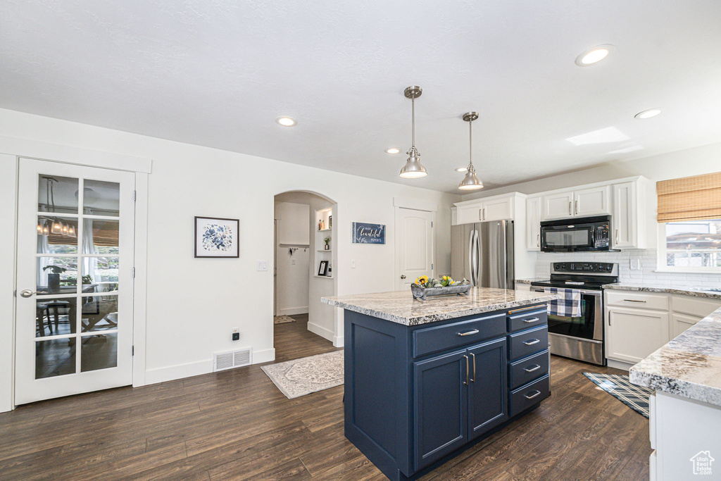 Kitchen featuring decorative light fixtures, light stone counters, white cabinetry, dark hardwood / wood-style floors, and stainless steel appliances