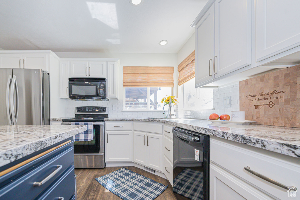 Kitchen featuring dark hardwood / wood-style floors, black appliances, white cabinets, and tasteful backsplash