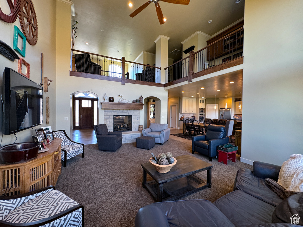 Carpeted living room with a fireplace, a high ceiling, and ceiling fan