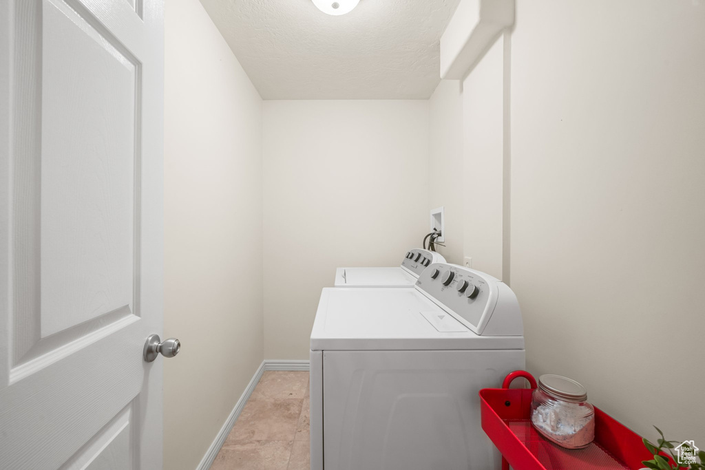 Washroom with light tile floors, washing machine and dryer, and hookup for a washing machine