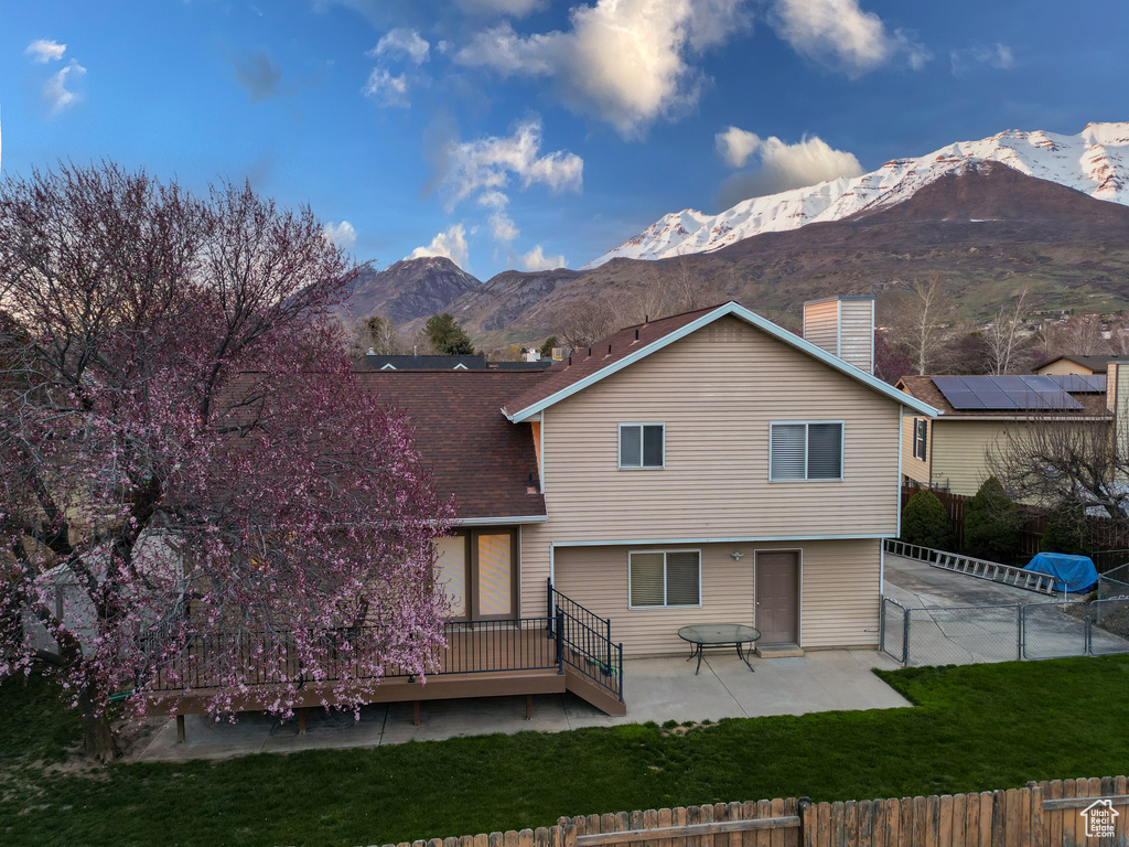 Back of property featuring a patio, a lawn, solar panels, and a mountain view