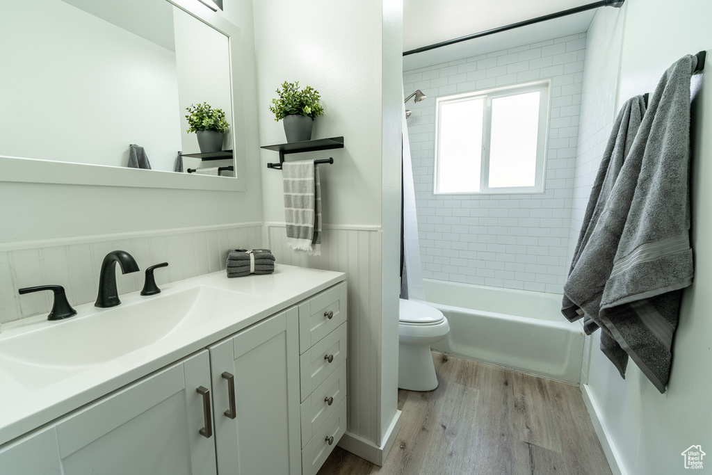Full bathroom with toilet, vanity, shower / tub combo with curtain, and hardwood / wood-style flooring