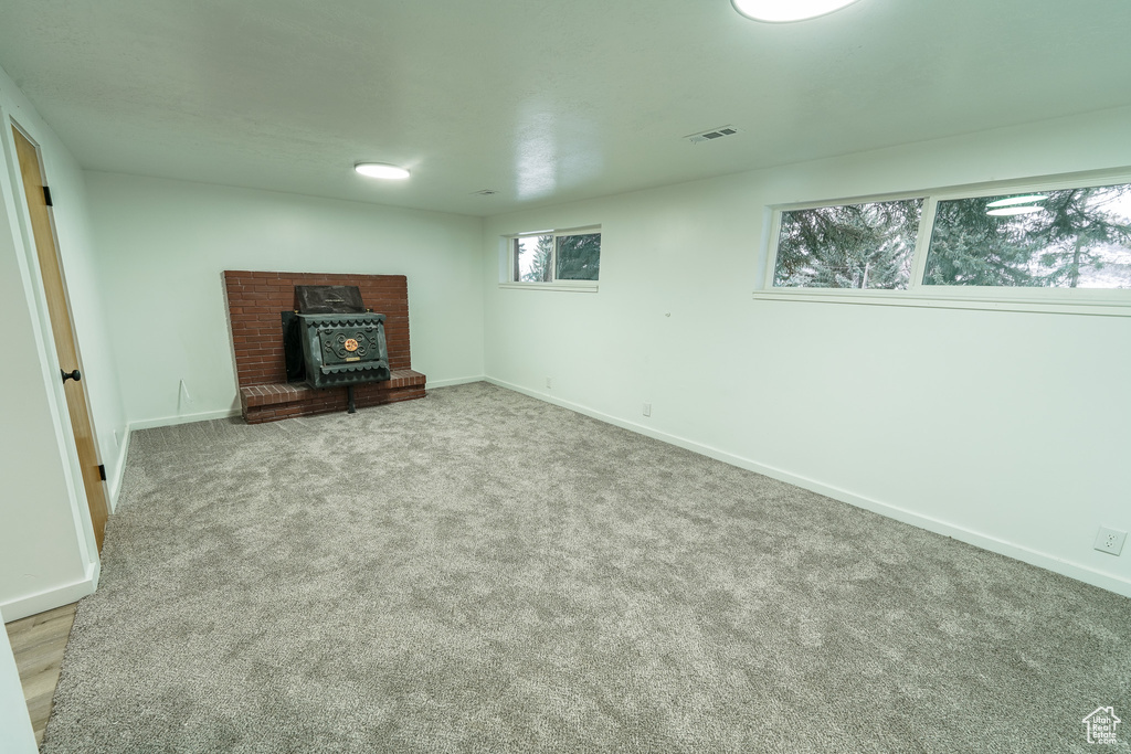 Unfurnished living room with a wood stove and light carpet