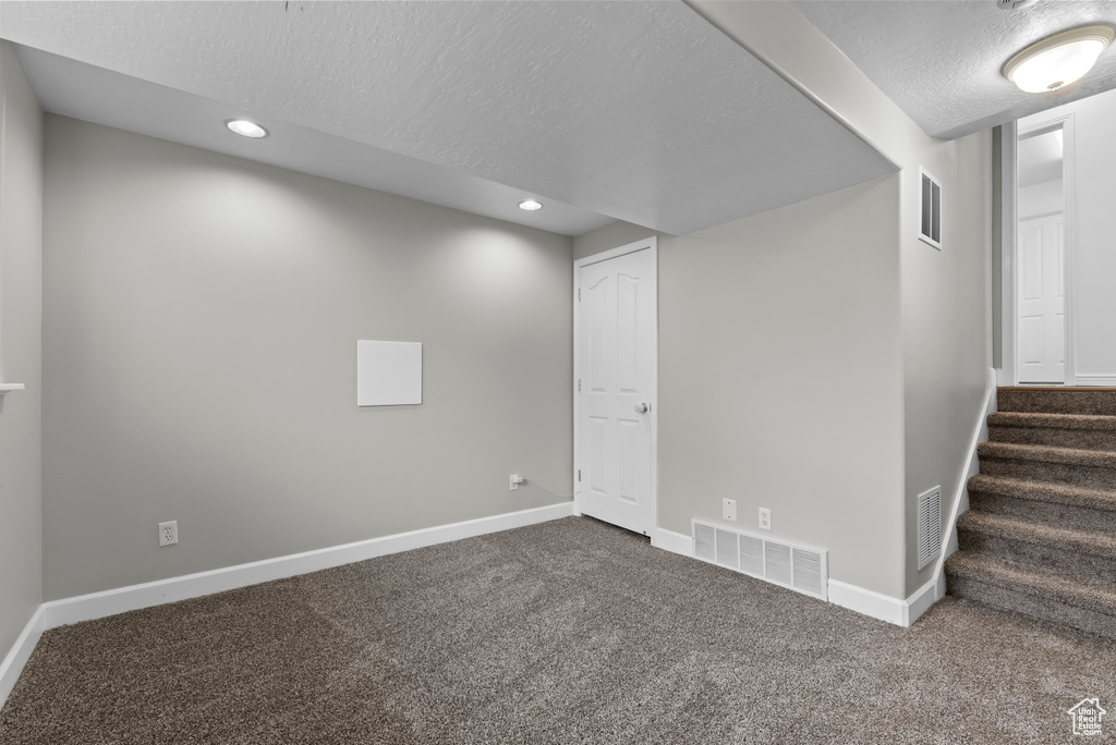 Basement featuring a textured ceiling and dark colored carpet