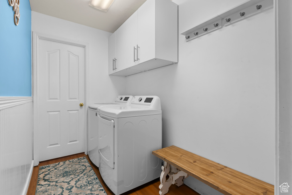 Clothes washing area featuring cabinets, washer and dryer, and hardwood / wood-style floors