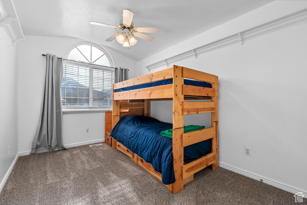 Bedroom with ceiling fan, lofted ceiling, and dark carpet