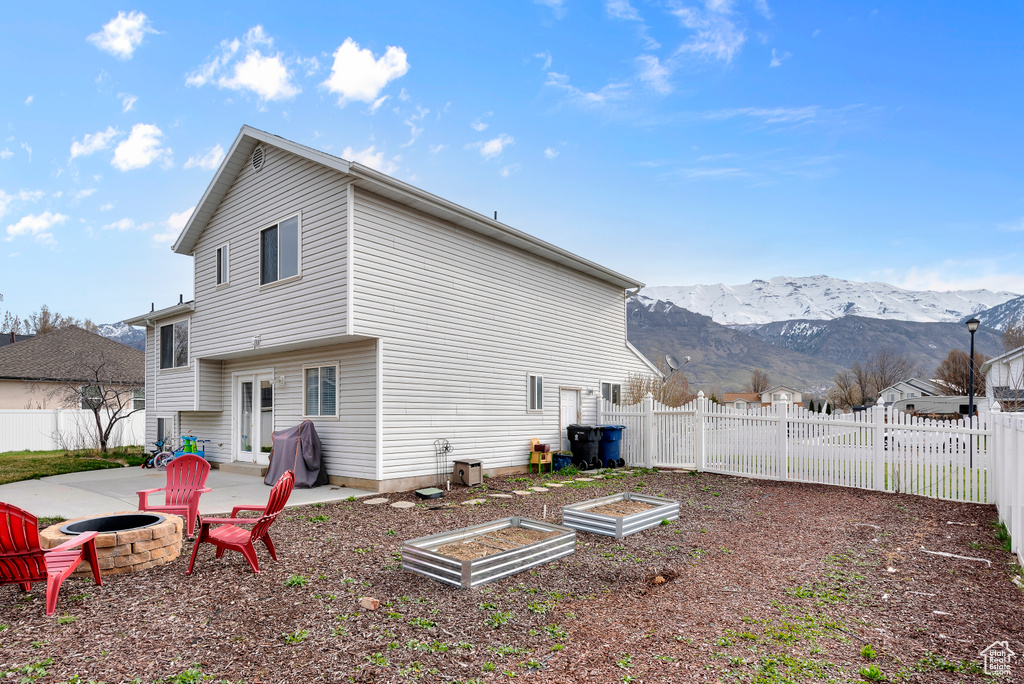 Back of property featuring an outdoor fire pit, a patio area, and a mountain view