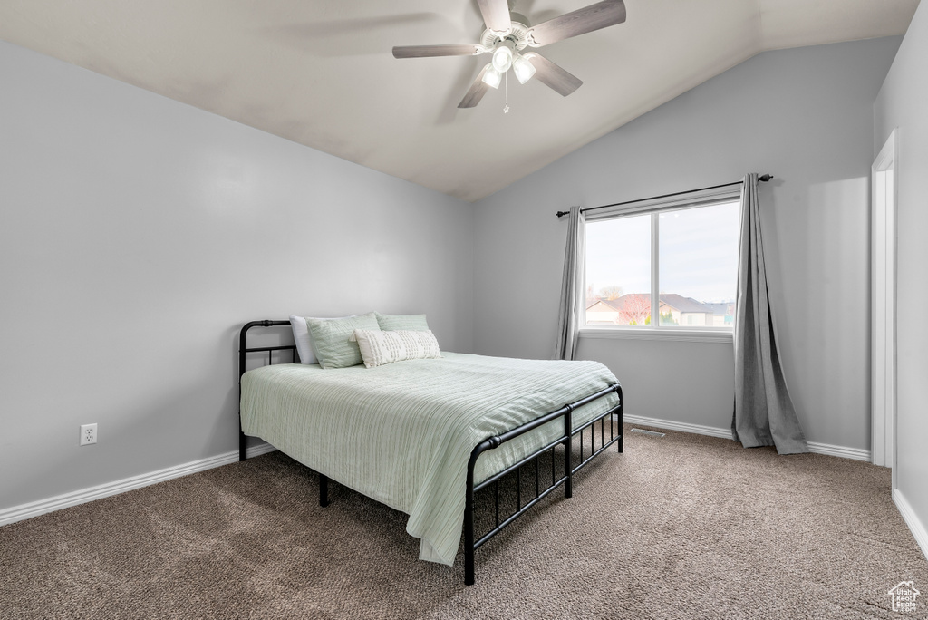 Bedroom with ceiling fan, light colored carpet, and vaulted ceiling