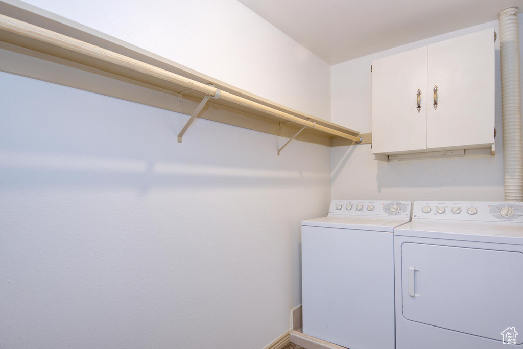Clothes washing area featuring cabinets and washer and clothes dryer