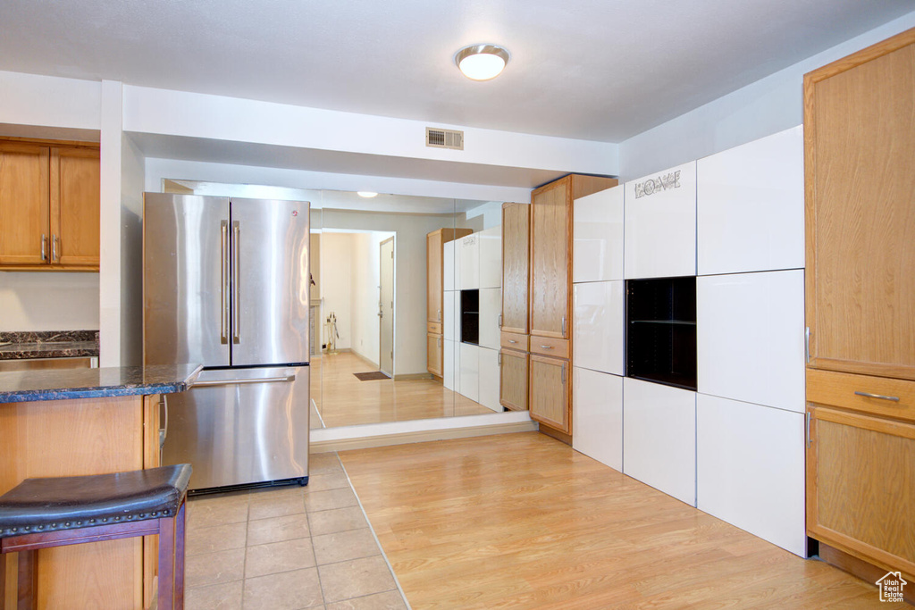 Kitchen with dark stone countertops, light tile floors, and stainless steel fridge