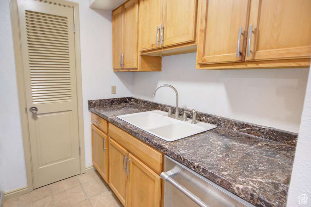 Kitchen featuring sink, stainless steel dishwasher, and light tile flooring