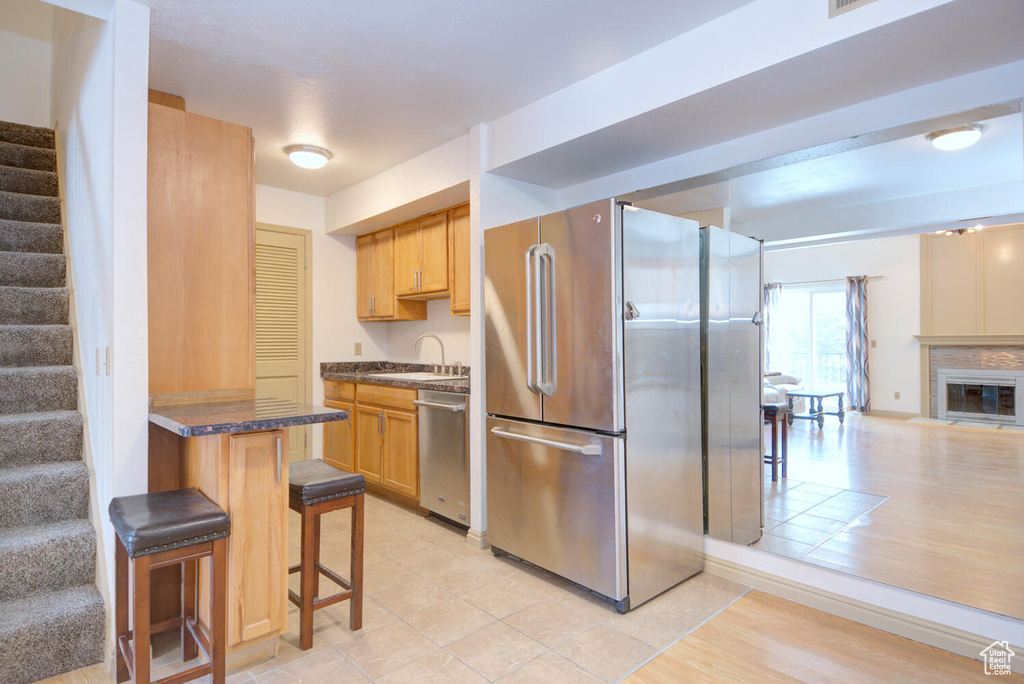 Kitchen with appliances with stainless steel finishes, a breakfast bar area, light tile floors, and sink