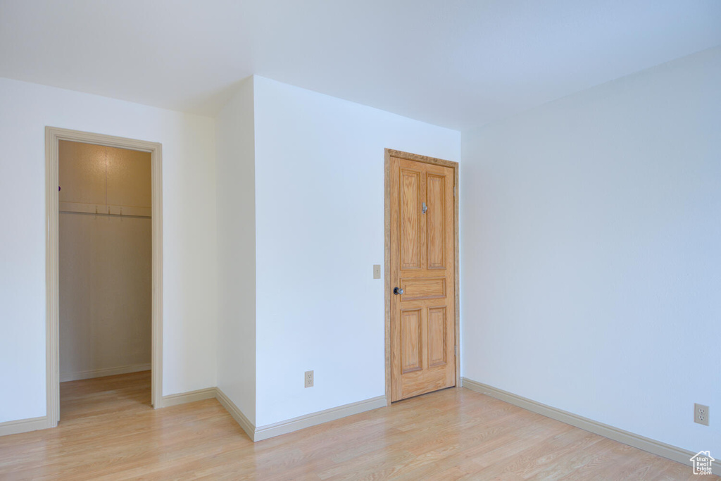 Unfurnished bedroom with a closet, a spacious closet, and light hardwood / wood-style flooring