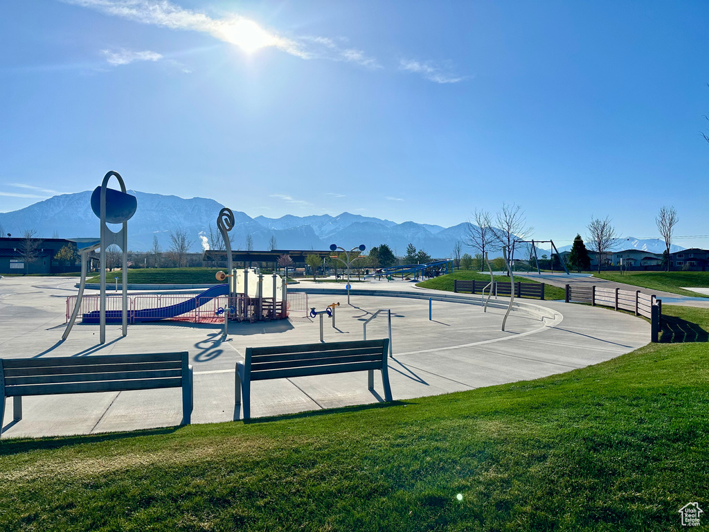 Surrounding community featuring a playground, a lawn, and a mountain view