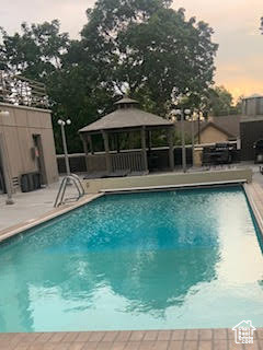 Pool at dusk featuring a gazebo