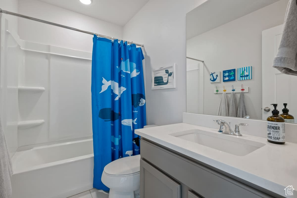 Full bathroom with shower / bath combination with curtain, tile flooring, toilet, and vanity with extensive cabinet space