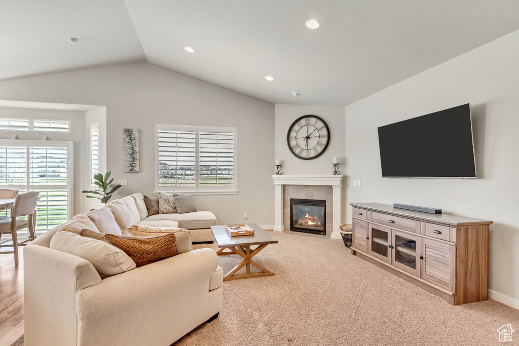 Living room with light colored carpet, vaulted ceiling, and a fireplace