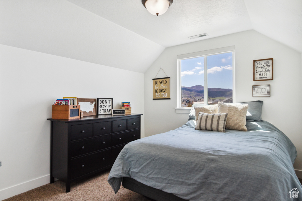Bedroom with light colored carpet and vaulted ceiling