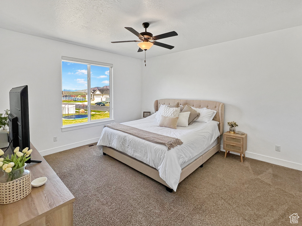 Bedroom featuring a textured ceiling, ceiling fan, and dark colored carpet