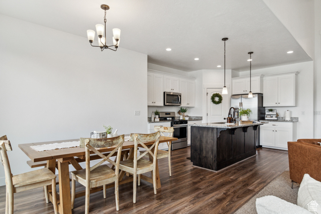 Kitchen featuring decorative light fixtures, a chandelier, dark hardwood / wood-style floors, stainless steel appliances, and light stone countertops