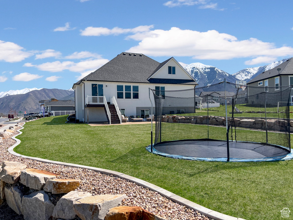 Exterior space with a mountain view, a trampoline, and a yard