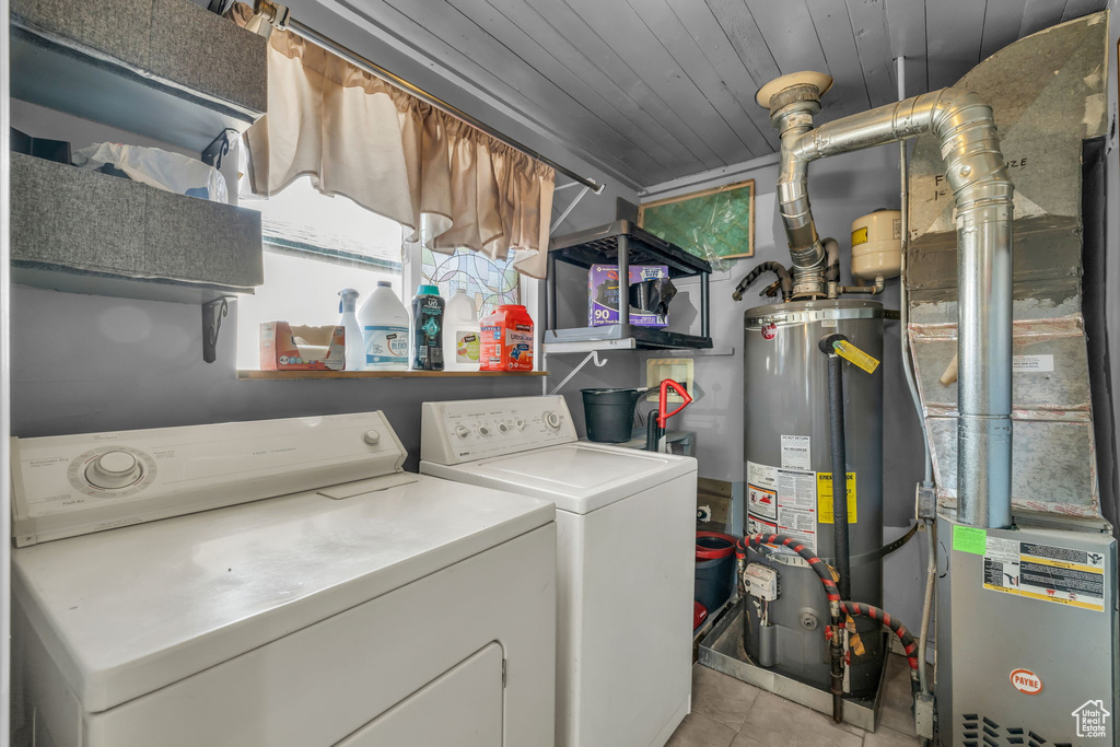 Laundry room featuring water heater, a healthy amount of sunlight, washer and dryer, and light tile floors