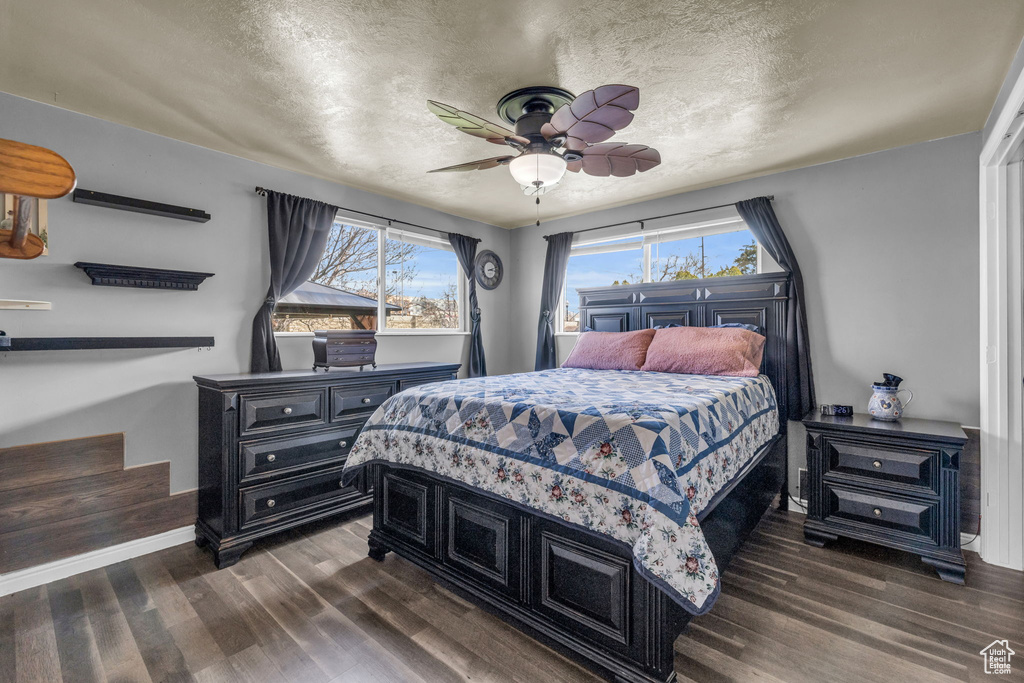 Bedroom with ceiling fan, dark hardwood / wood-style floors, and a textured ceiling
