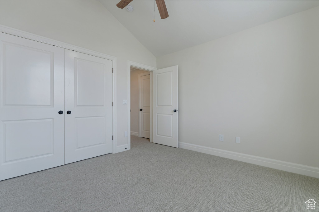 Unfurnished bedroom featuring a closet, carpet floors, ceiling fan, and high vaulted ceiling